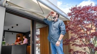 Ein Mann steht im Garten und schaut auf die Markise