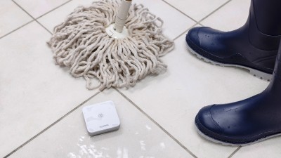 Wassermelder auf nassem Boden neben einem Wischmopp