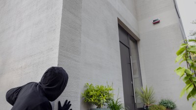 Un cambrioleur lorgne une porte d'entrée équipée d'un système d'alarme