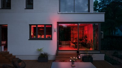 Ein Blick durch große Fenster in eine rot beleuchteten Wohnung