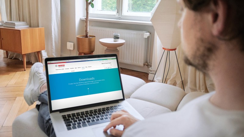 Ein Mann ruft die Bosch Smart Home Hilfe Website auf dem Notebook auf