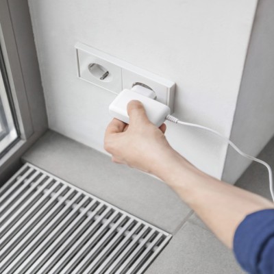 Une main branche un adaptateur secteur dans une prise