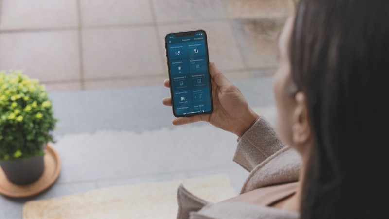 Eine Frau, die über ihre Smartphone App den Status ihrer Smarthome-Geräte prüft