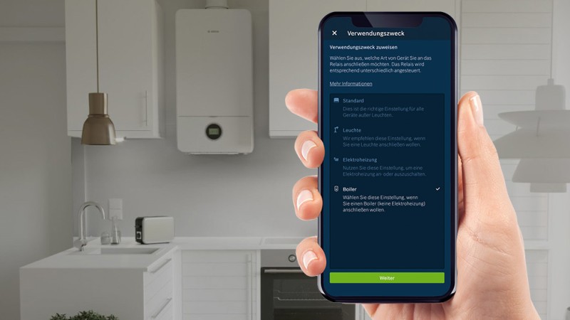 Smartphone mit Bosch Smart Home App vor einem Boiler