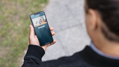 Een vrouw heeft een smartphone met de Bosch Smart Home-app in haar hand